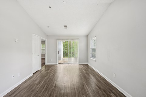 A room with white walls and wooden flooring with a sliding glass door.