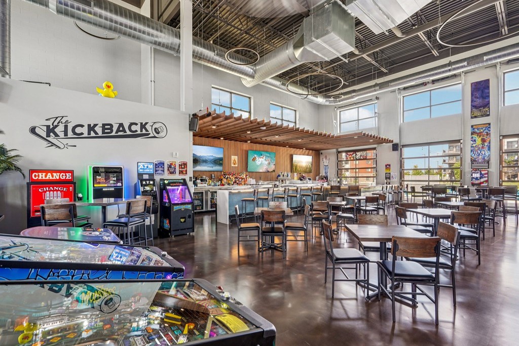 A room with a pinball machine and a sign that says Kickback.