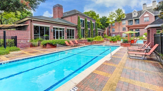 a large swimming pool in front of a brick house