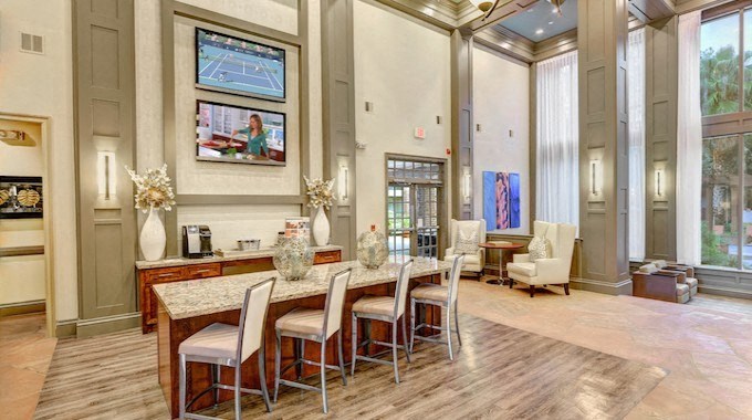 A dining room with a table set for four and a television mounted on the wall.