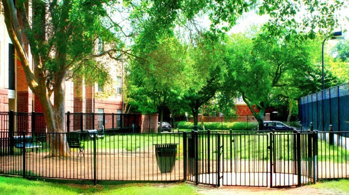 A black fence surrounds a green park area.
