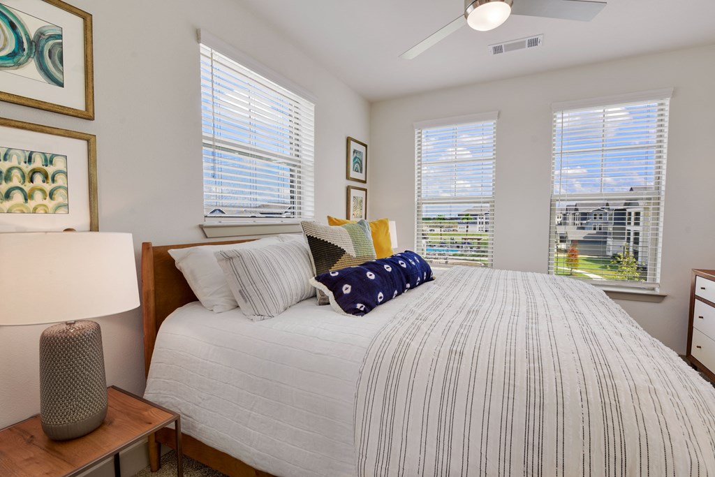 a bedroom with a large bed and three windows