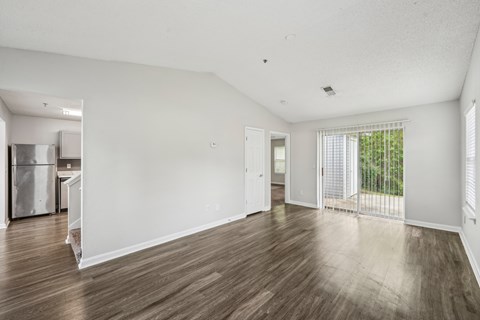 A spacious room with wooden flooring and white walls.