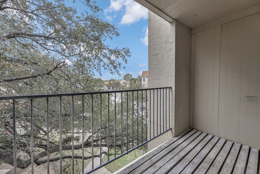A balcony with a black railing and wooden floor.