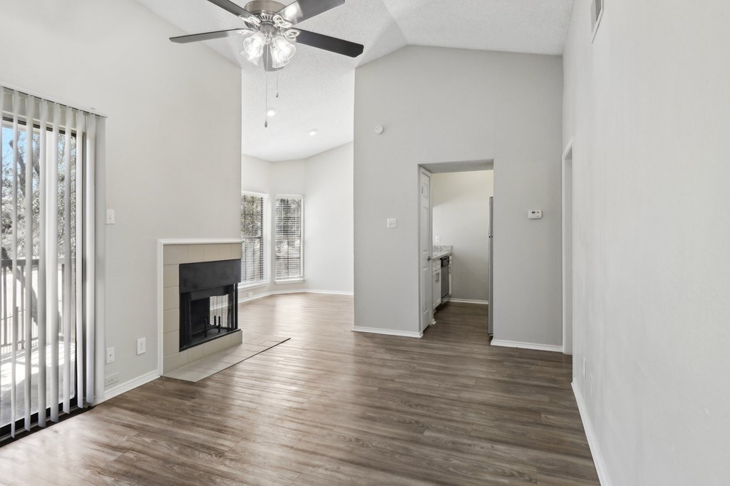 A spacious living room with a fireplace and a ceiling fan.