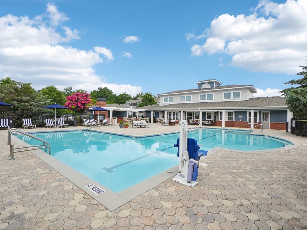 A large swimming pool with a blue lounge chair and a white pole.