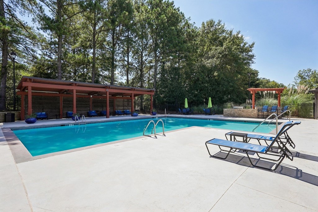 A pool with a bench and a building in the background.
