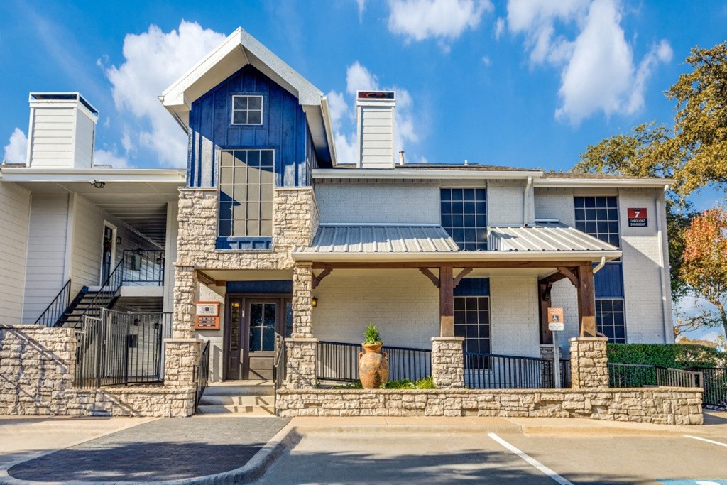a blue and white building with a porch and a blue sky