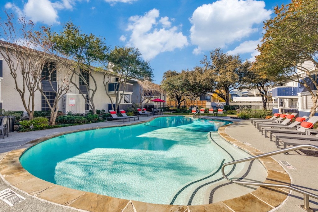 a swimming pool with chairs around it in front of a building