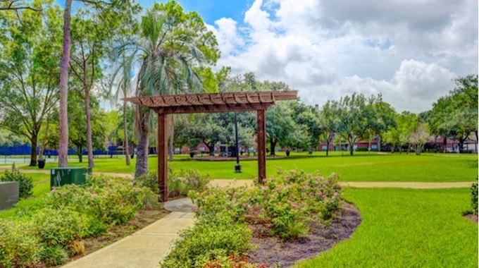 A park with a wooden pergola and a pathway.