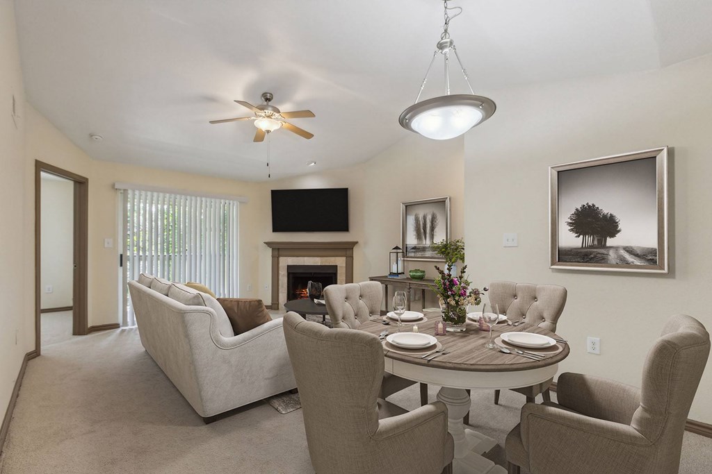 A living room with a fireplace, a couch, a chair, a dining table and a television.