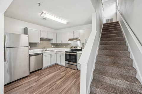 A kitchen with a staircase leading to the upper floor.