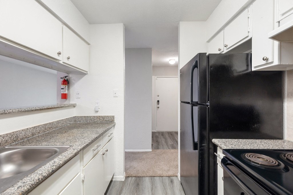 a kitchen with white cabinets and a black refrigerator