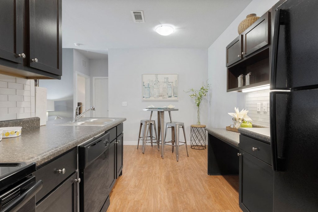 A kitchen with black cabinets and a black fridge.
