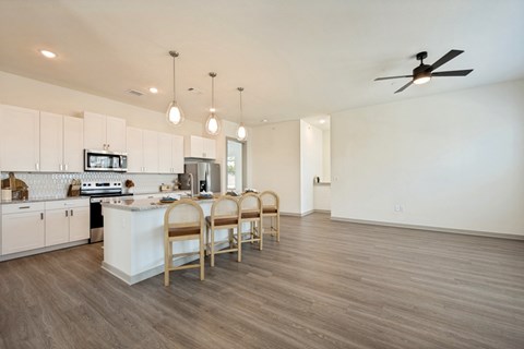 A kitchen with a white counter and wooden chairs.
