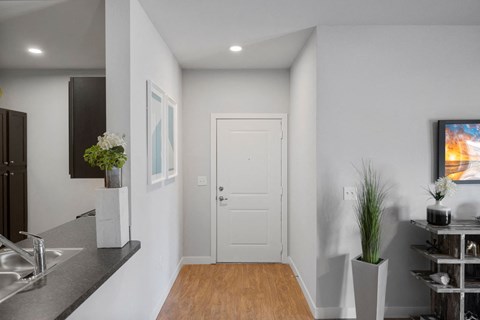 a hallway with a white door and a kitchen with a sink