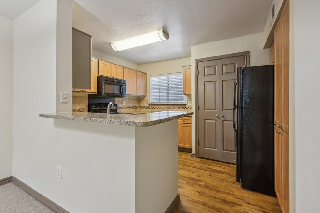A kitchen with a black fridge and microwave.