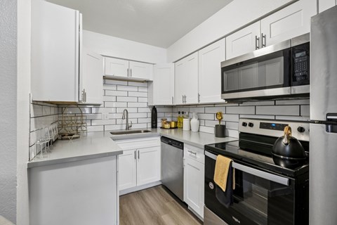 A modern kitchen with white cabinets and stainless steel appliances.