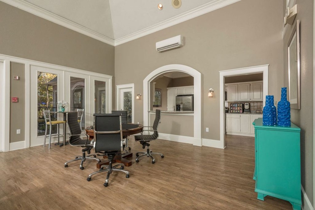 a conference room with a table and chairs and a kitchen in the background