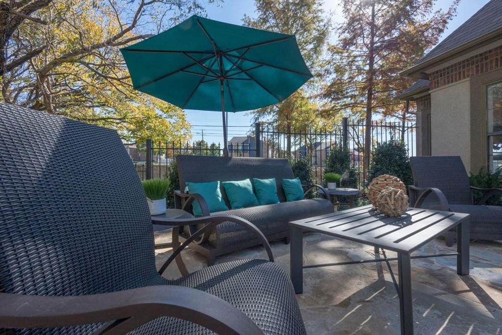 a patio with chairs and a table with an umbrella