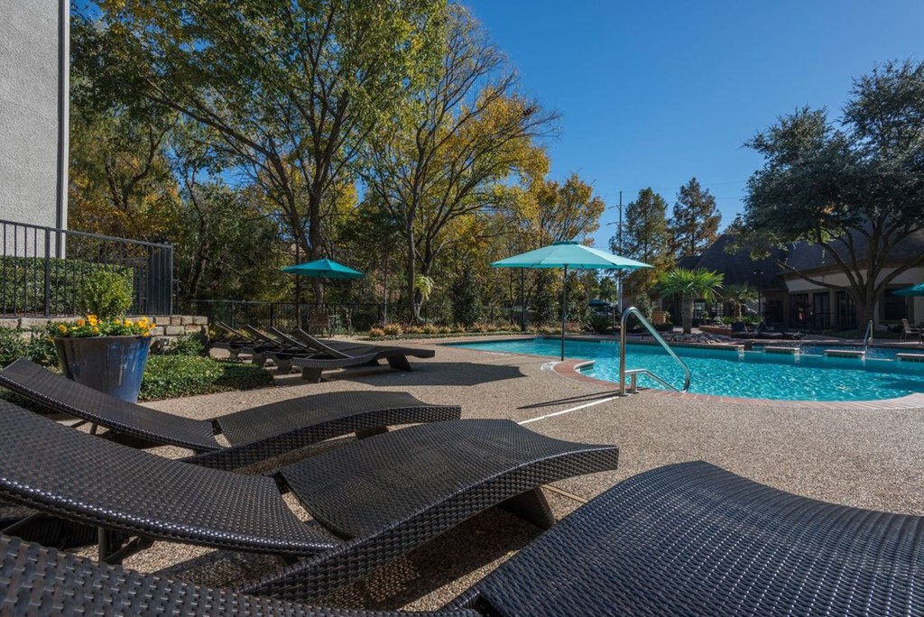 a swimming pool with lounge chairs and umbrellas