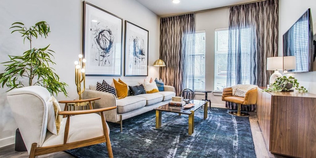 A modern living room with a white sofa, wooden chairs, and a coffee table.