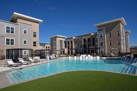 A large swimming pool in front of apartment buildings.