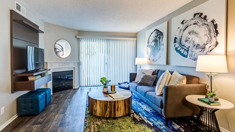 A living room with a blue couch, a wooden coffee table, and a large painting on the wall.