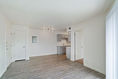 an empty living room and kitchen with a wood floor