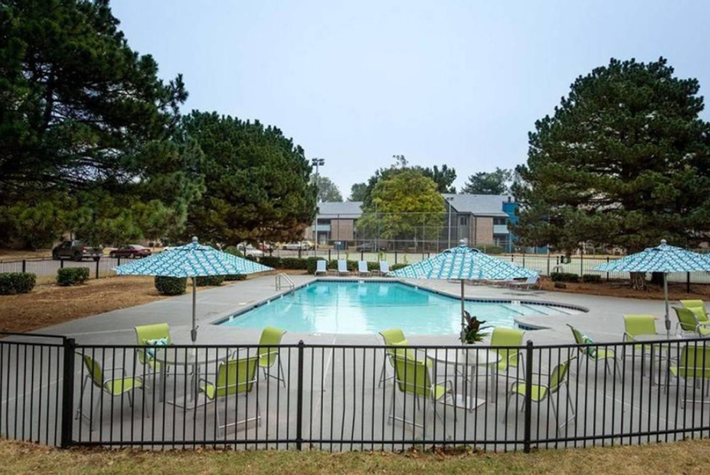 a swimming pool with green chairs and umbrellas