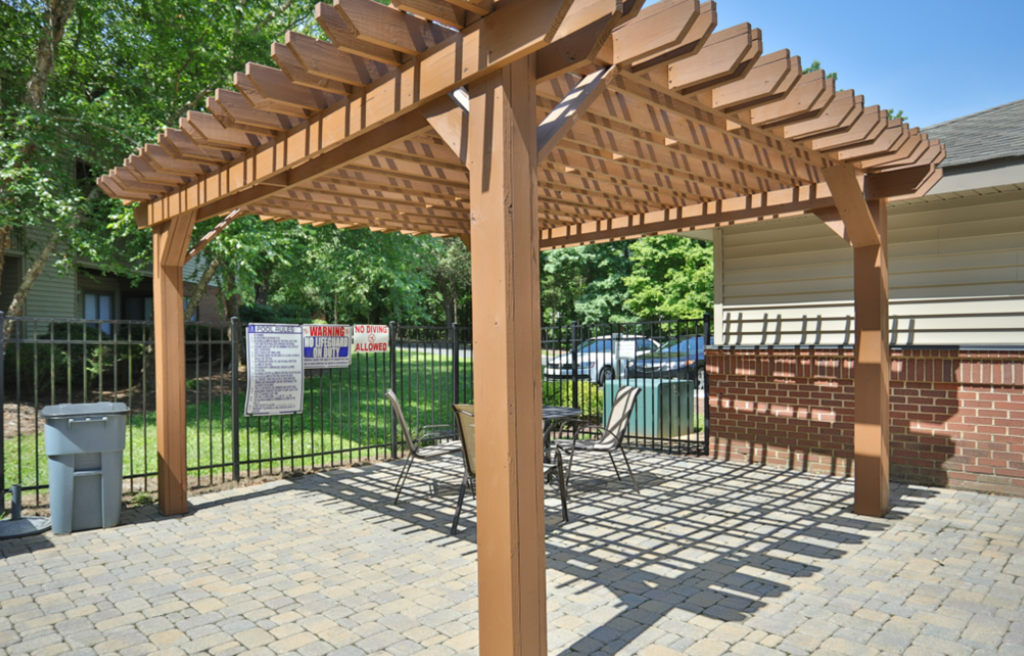 a covered patio with a table and chairs under a wooden pergola