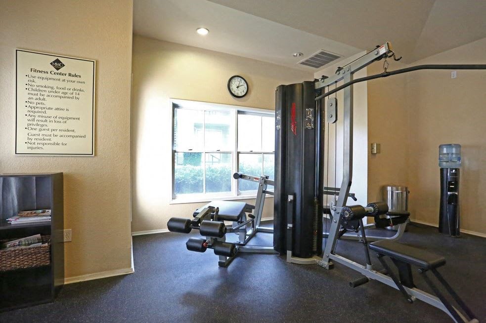 a gym with weights and a window and a clock on the wall