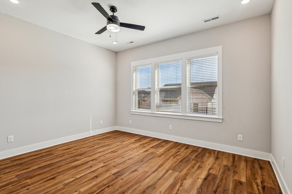 A room with a ceiling fan and wooden flooring.