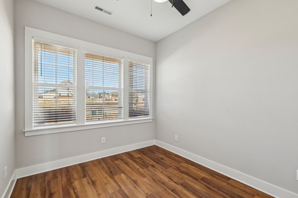 A room with wooden floors and a window with blinds.