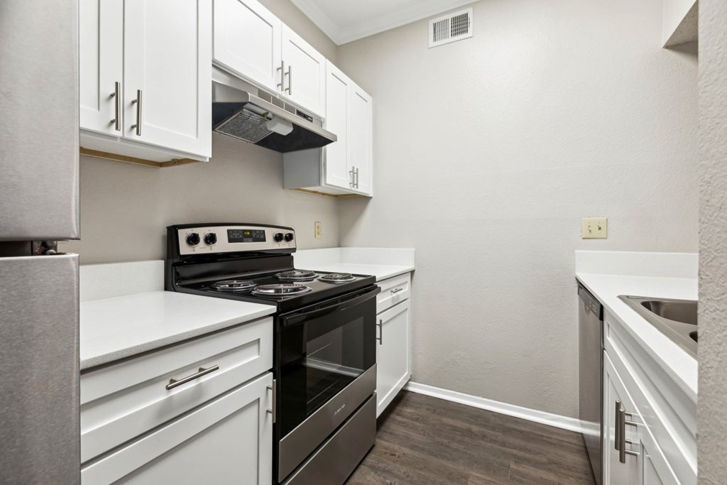A kitchen with white cabinets and a black stove top oven.