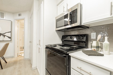A modern kitchen with a black stove and white cabinets.