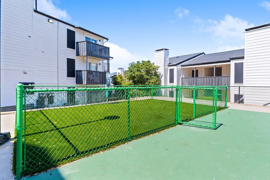 the private tennis court is fenced in with a green fence