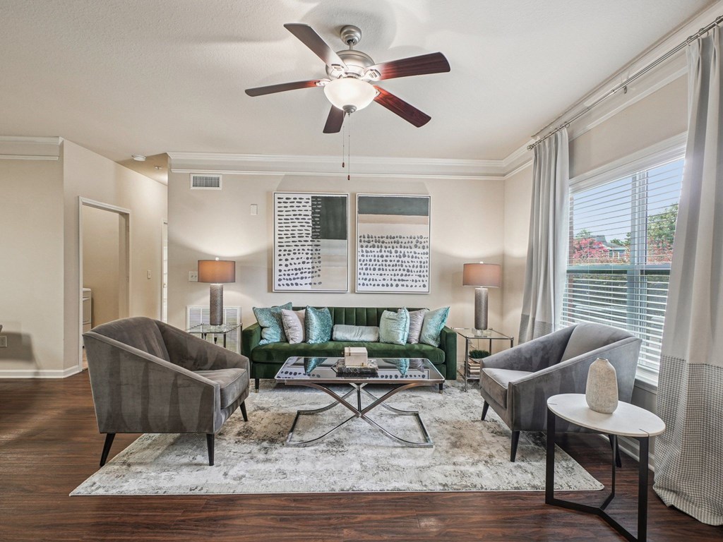A living room with a green couch, grey armchair, and a white side table.