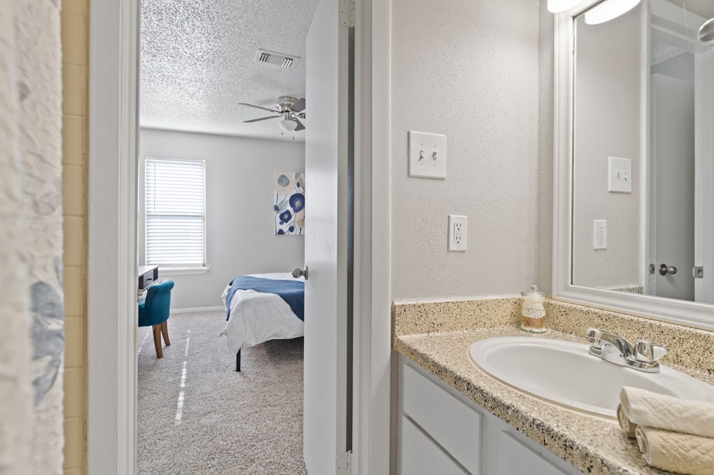 A bathroom with a blue bed in the background.
