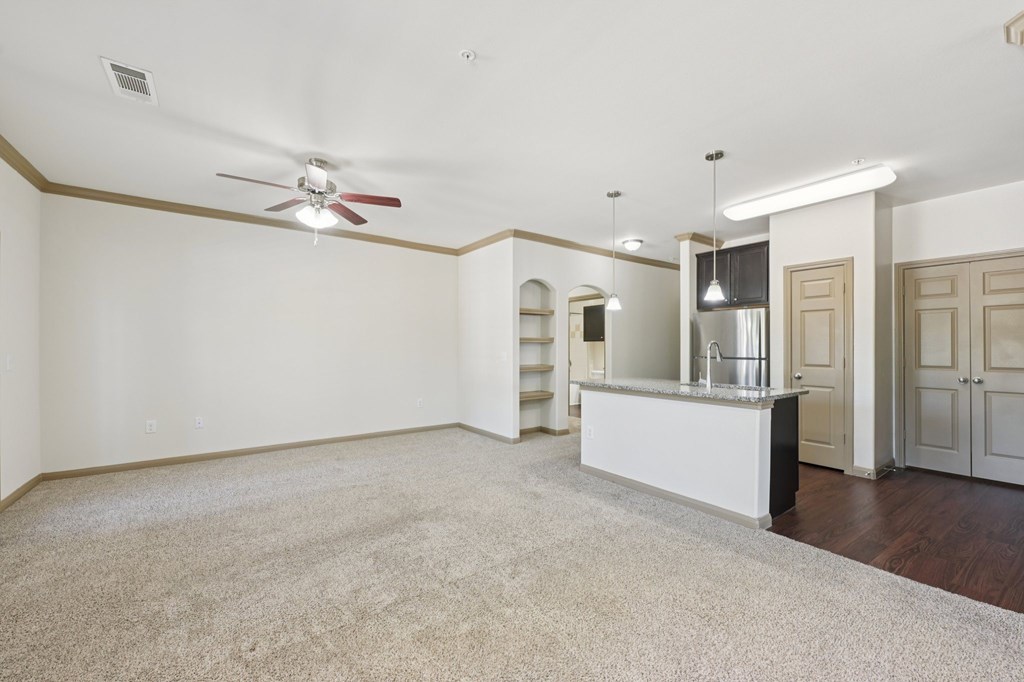 A spacious room with a ceiling fan and a bar area.