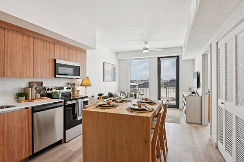A modern kitchen with wooden cabinets and a dining table set for a meal.