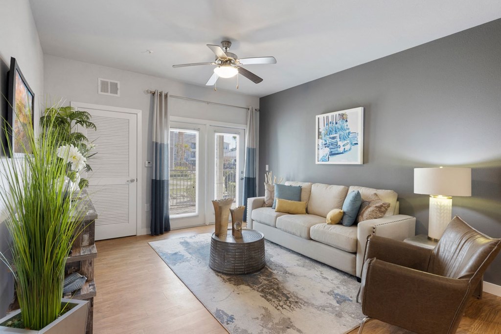 A living room with a couch, chair, and potted plant.