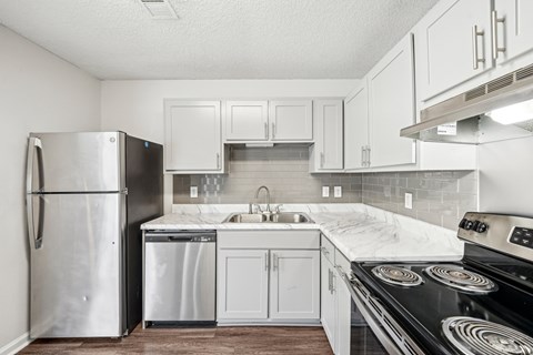A kitchen with a stove, refrigerator, and dishwasher.