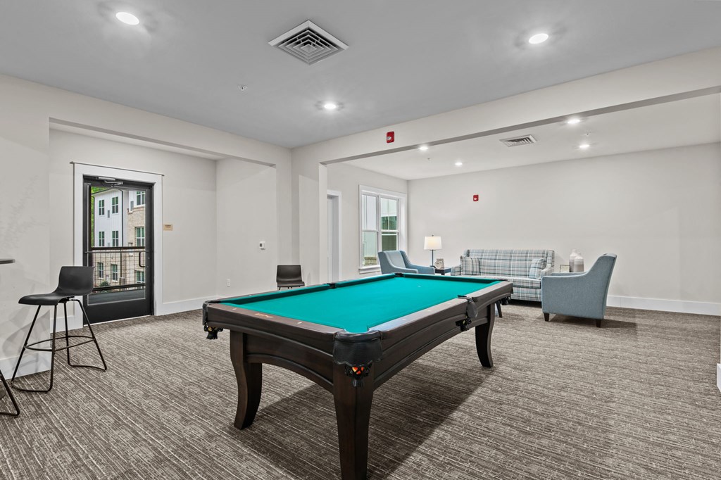 a games room with a pool table and chairs