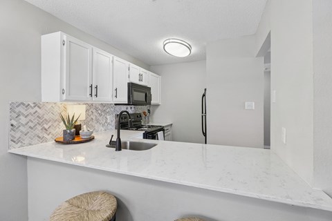 A kitchen with white cabinets and a marble countertop.