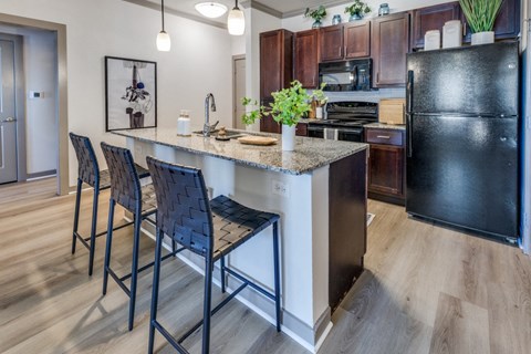 A kitchen with a black refrigerator and a marble countertop.