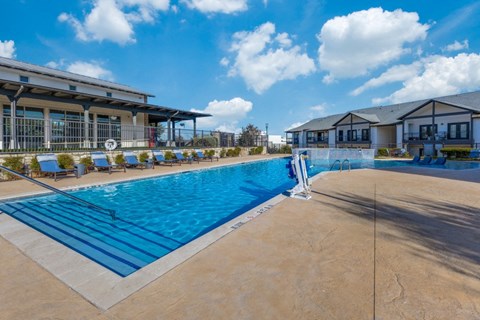 a swimming pool with chairs and a building in the background