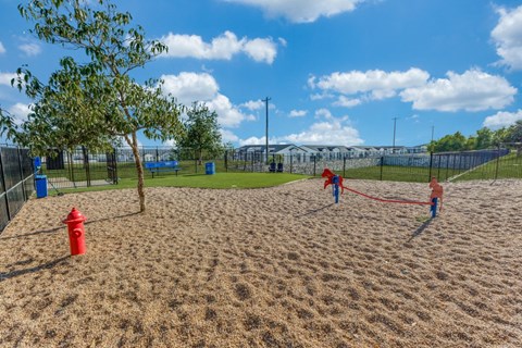 two children playing on a sand volleyball court at a park