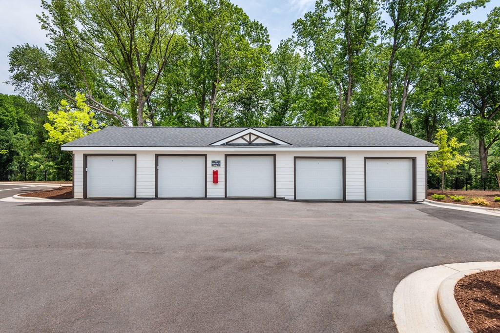 a white garage with white doors in front of trees