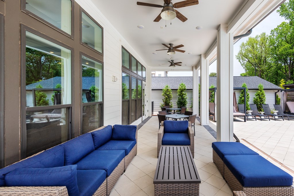 a covered patio with blue couches and a table and chairs